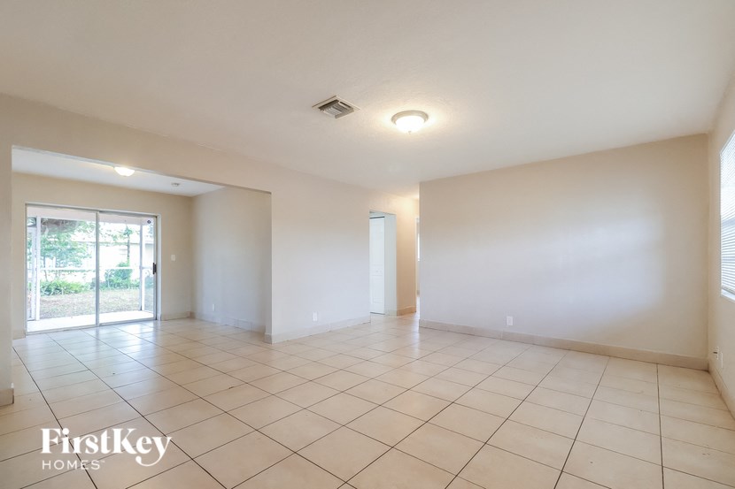 a spacious living room with tiled flooring and a door to the patio