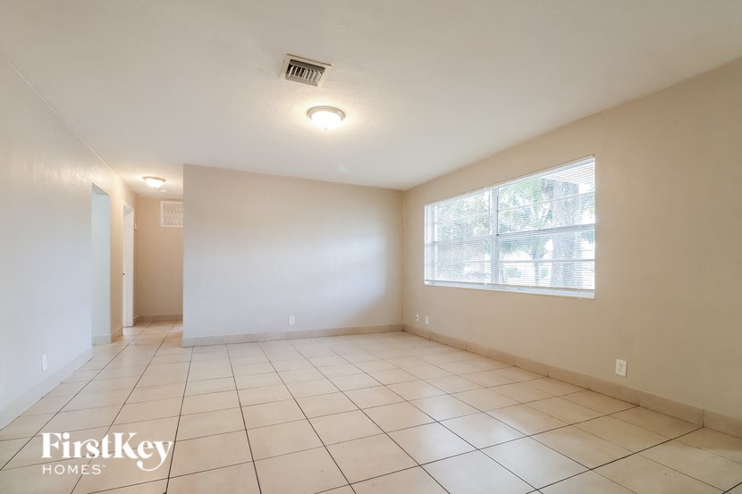 an empty living room with a large window and tiled floors