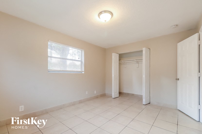 an empty living room with a white tile floor and a closet