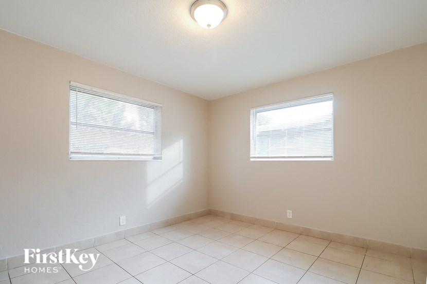 an empty room with two windows and a tiled floor