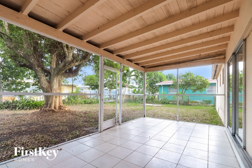 a covered porch with sliding glass doors and a tree