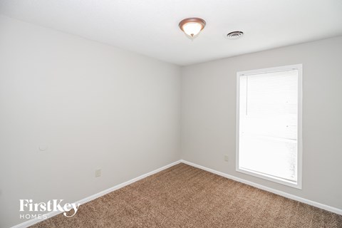 a bedroom with white walls and carpet and a window