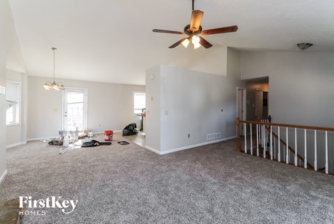 A spacious room with a ceiling fan and a carpeted floor.