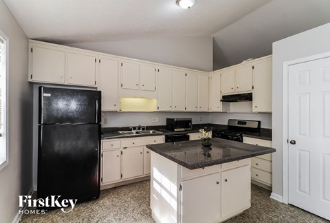 A kitchen with a black fridge and white cabinets.