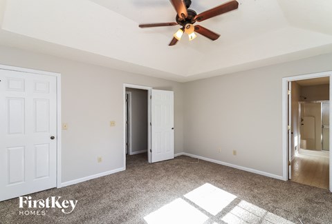 A room with a ceiling fan and a carpeted floor.