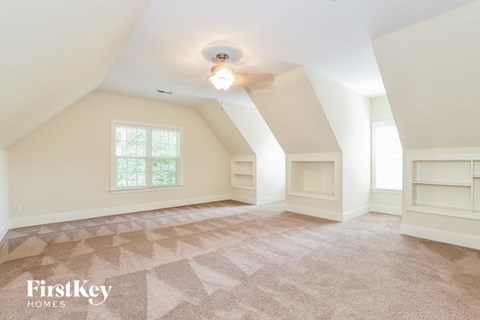 A room with a carpeted floor and a window with a view of trees.