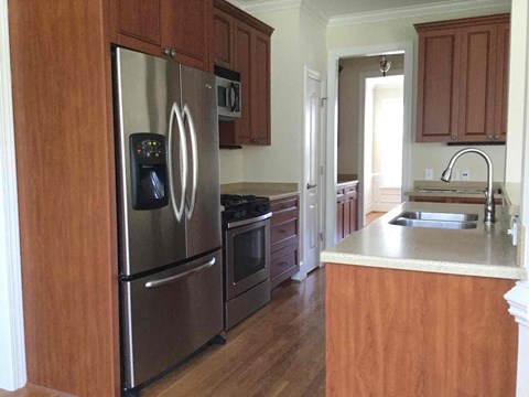 A kitchen with a stainless steel refrigerator and wooden cabinets.