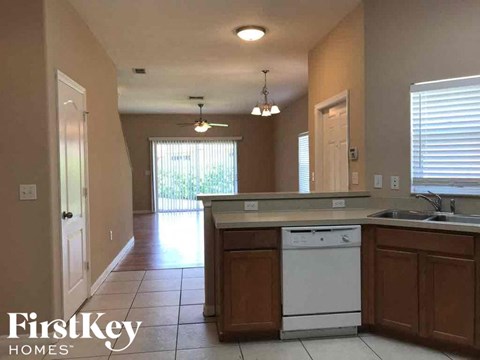 A kitchen with a white dishwasher and brown cabinets.