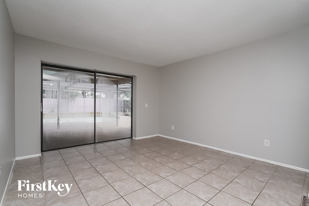 the living room of an empty home with a large tile floor and sliding glass doors