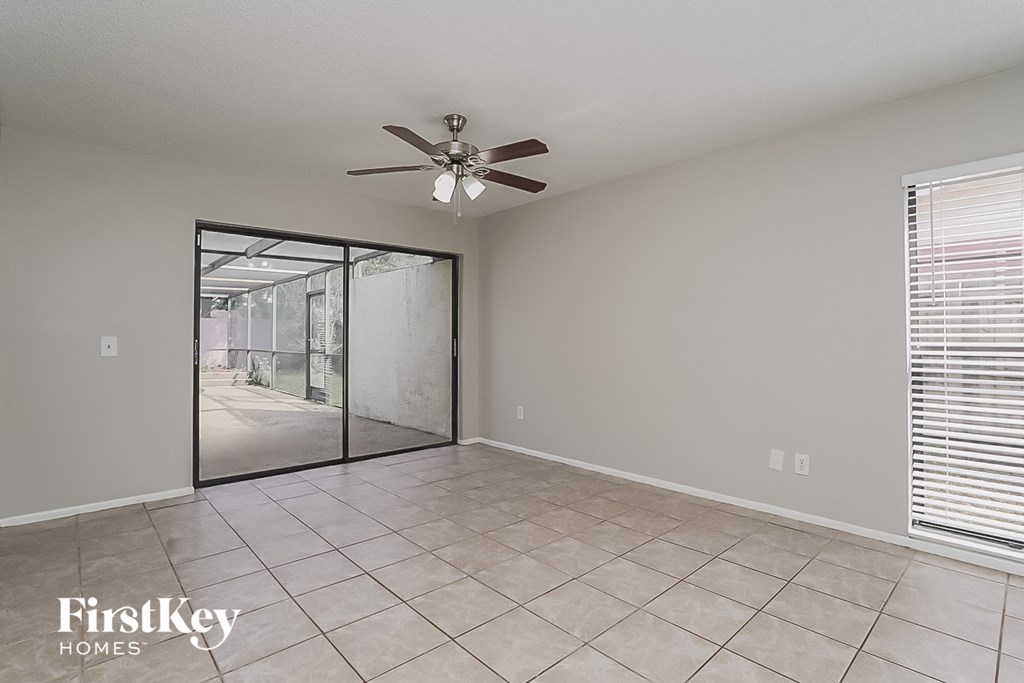 an empty living room with a ceiling fan and a sliding glass door