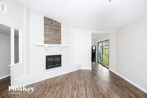 A spacious room with a fireplace and wooden flooring.