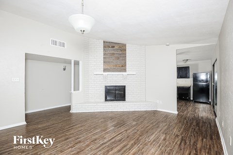 A living room with a fireplace and wood flooring.