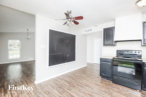 A kitchen with a black fridge and stove top oven.