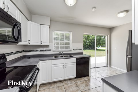 A kitchen with white cabinets and black appliances.