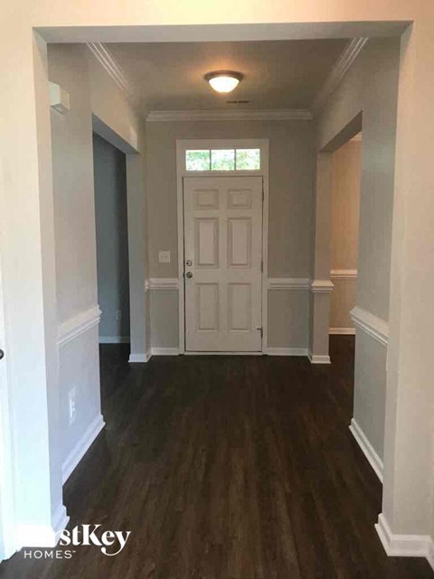 a view of a hallway with a white door and wood floors