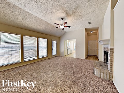 A spacious room with a fireplace and a ceiling fan.