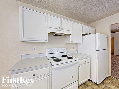 A kitchen with white appliances and cabinets.