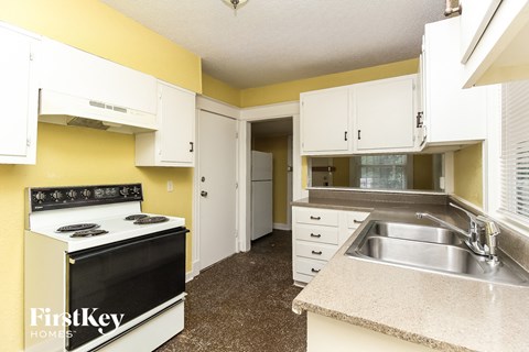 a kitchen with white cabinets and a stove and a sink