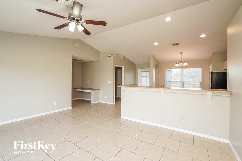 A spacious living room with a ceiling fan and tiled flooring.