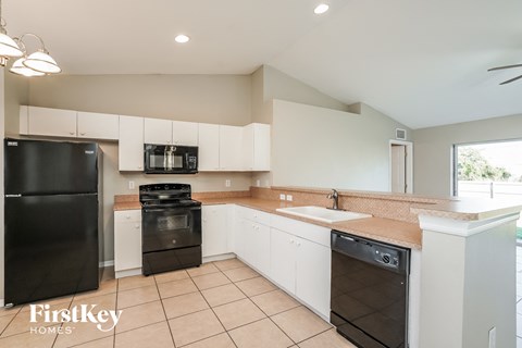 A kitchen with black appliances and white cabinets.