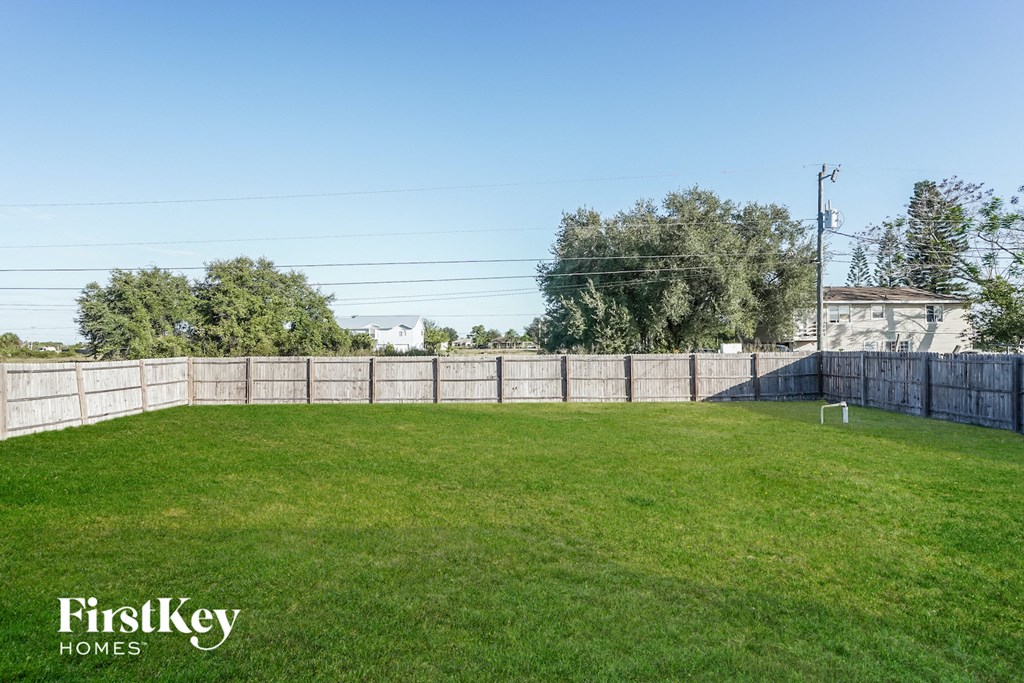 A grassy field with a fence and trees in the background.
