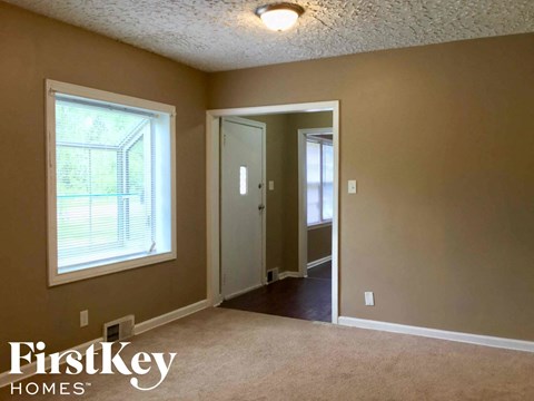 an empty living room with a large window and a door to a hallway