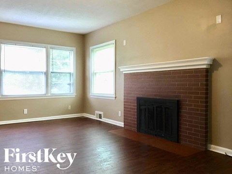 a living room with a brick fireplace and wooden floors