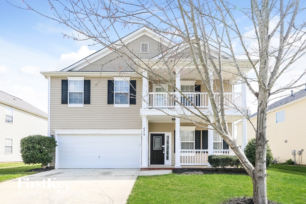 a yellow house with a porch and a tree in front of it