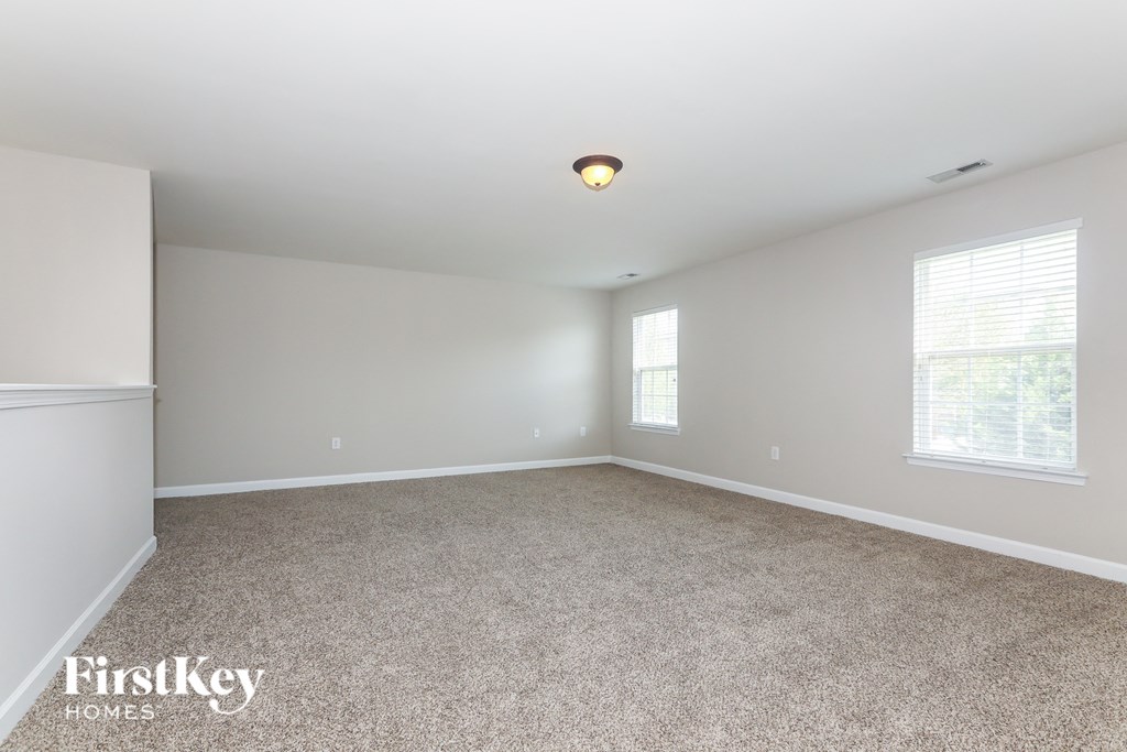 a empty living room with carpet and two windows