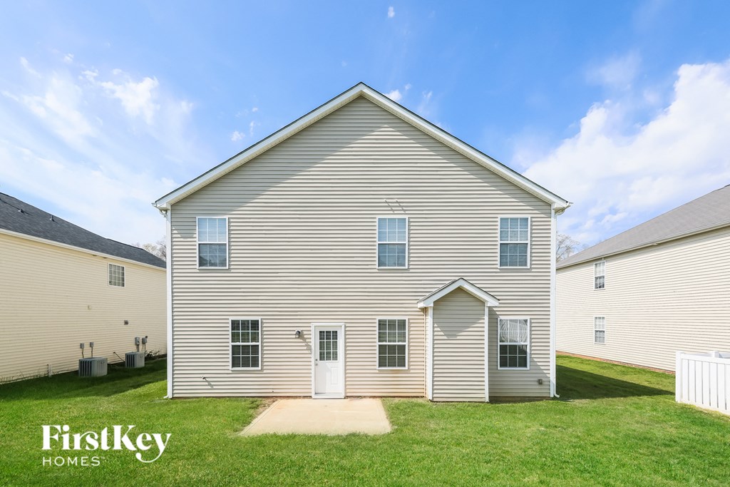side view of a white house with white siding and green grass