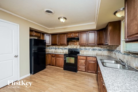 A kitchen with wooden cabinets and a black refrigerator.