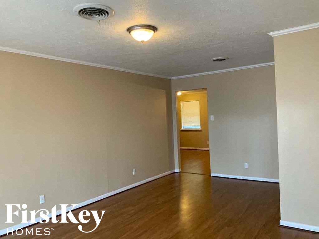 A room with wooden floors and a doorway leading to another room.