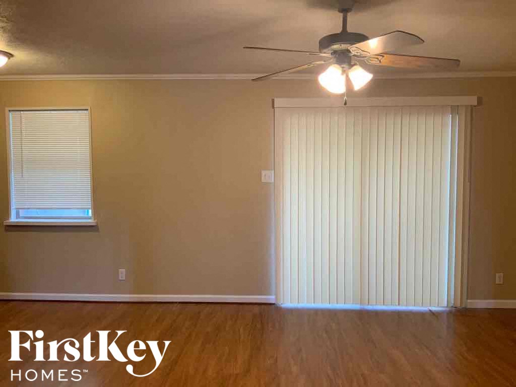 A room with a ceiling fan and a window with blinds.