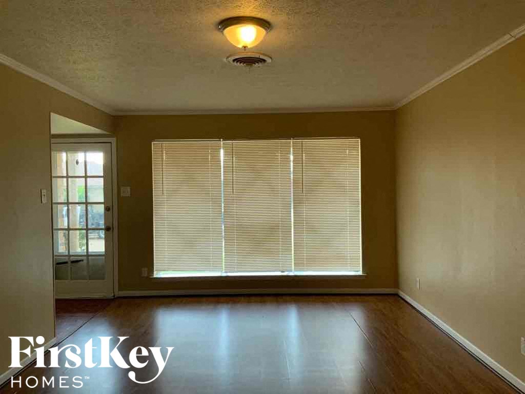 A room with a wooden floor and a window with blinds.