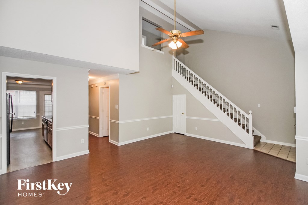 A spacious living room with wood floors and a staircase leading to the upper level.