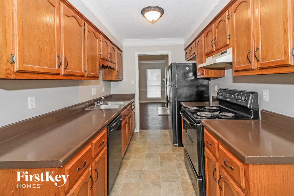 A kitchen with wooden cabinets and a black refrigerator.