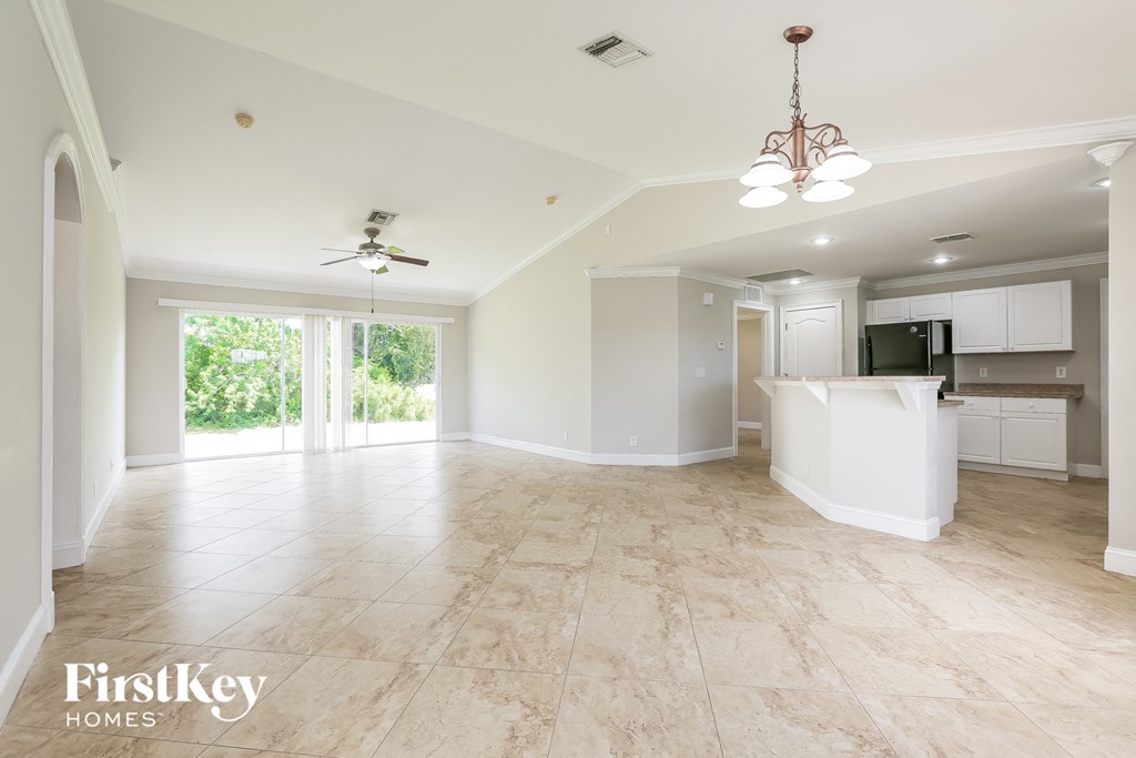 A spacious living room with a kitchen in the background.