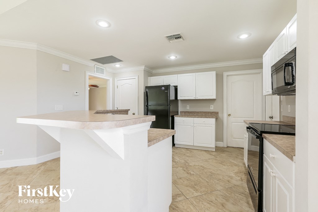 A kitchen with a white island and black appliances.