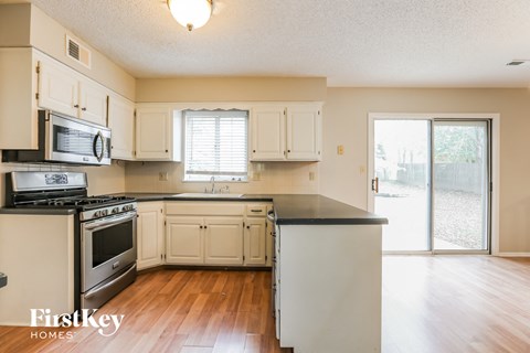 A kitchen with white cabinets and a black countertop.
