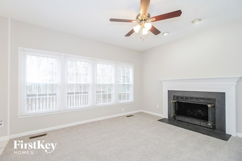 A living room with a fireplace and a ceiling fan.