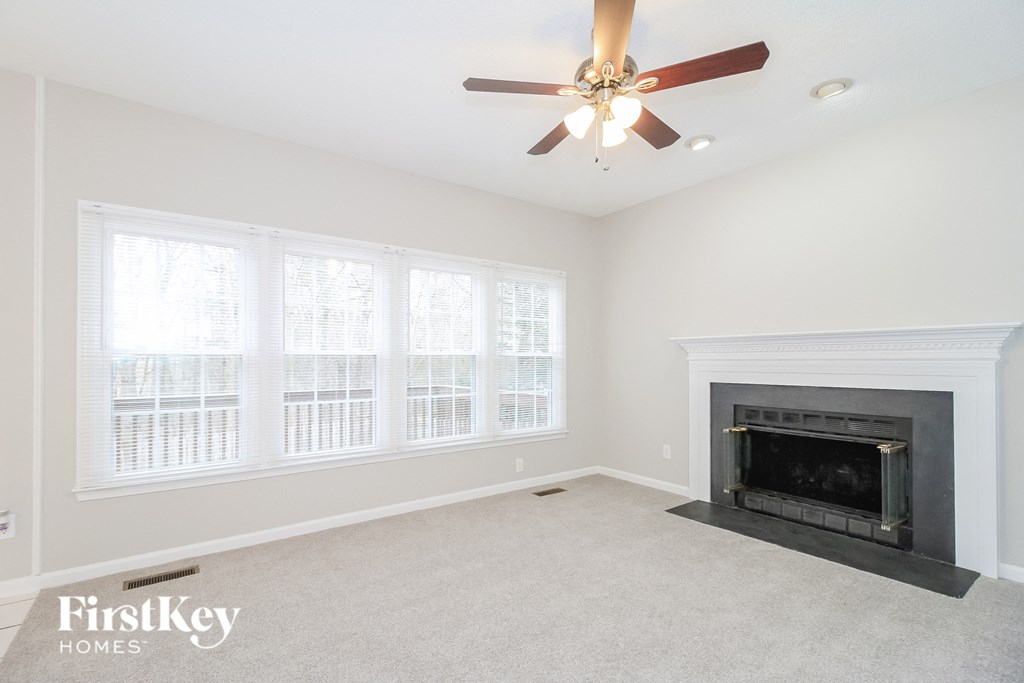 A living room with a fireplace and a ceiling fan.