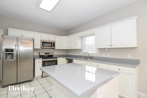 A kitchen with white cabinets and a stainless steel refrigerator.