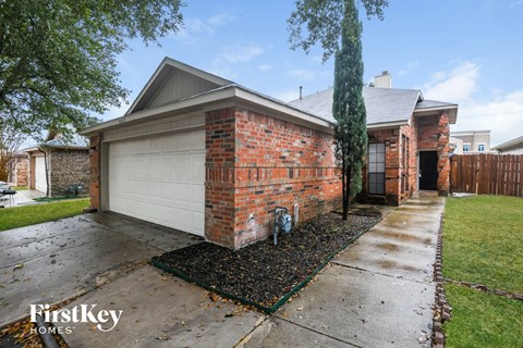 a brick house with a white garage door and a sidewalk