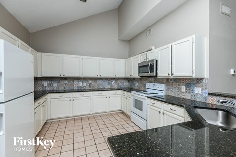a kitchen with white cabinets and granite counter tops