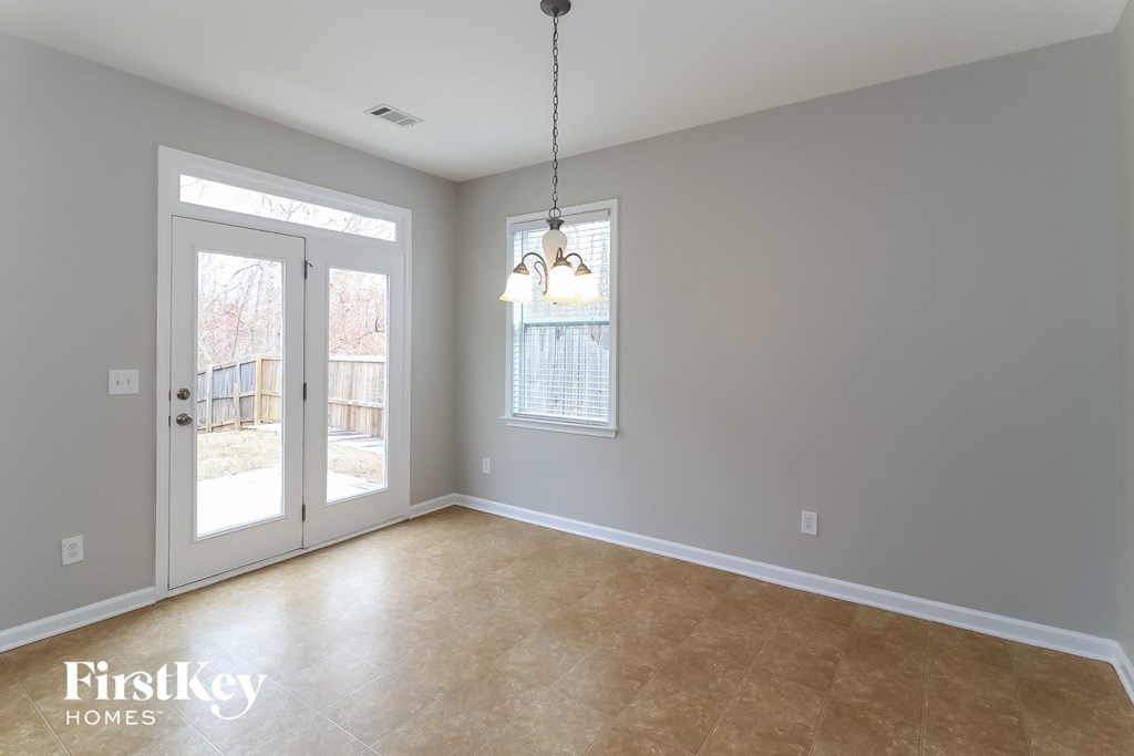 an empty living room with a sliding glass door and a chandelier
