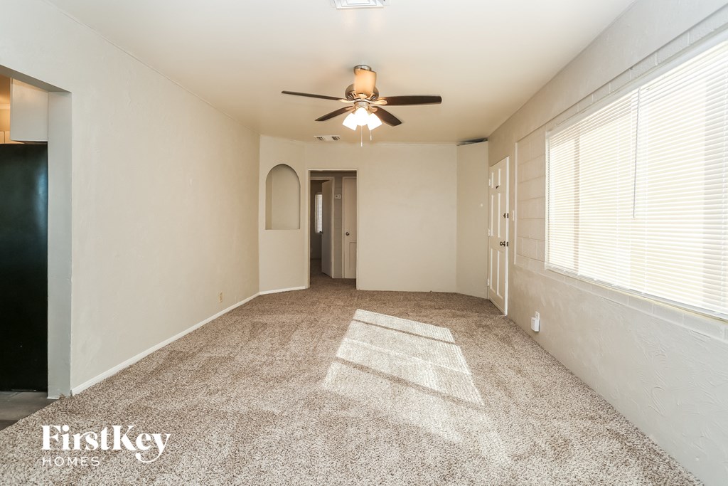 A spacious room with a ceiling fan and carpeted floor.