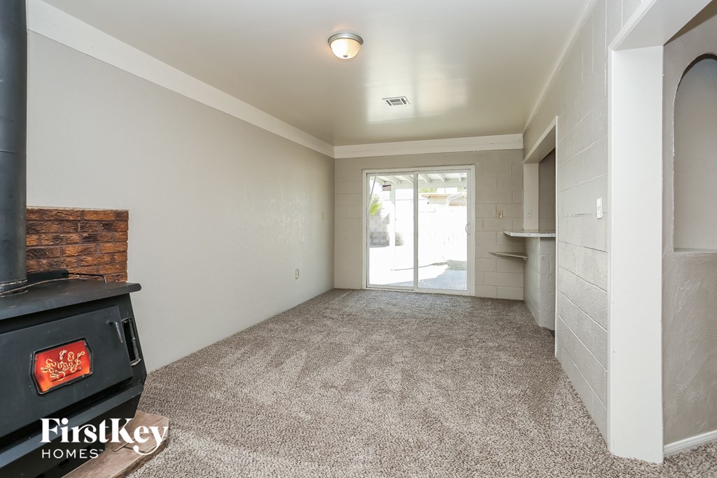 A room with a wood burning stove and a carpeted floor.