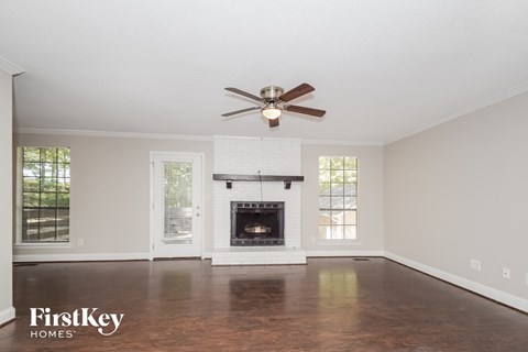 A spacious living room with a fireplace and a ceiling fan.