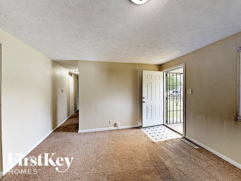 A carpeted room with a door and a window.