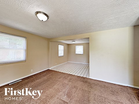 A room with a carpeted floor and a window with blinds.